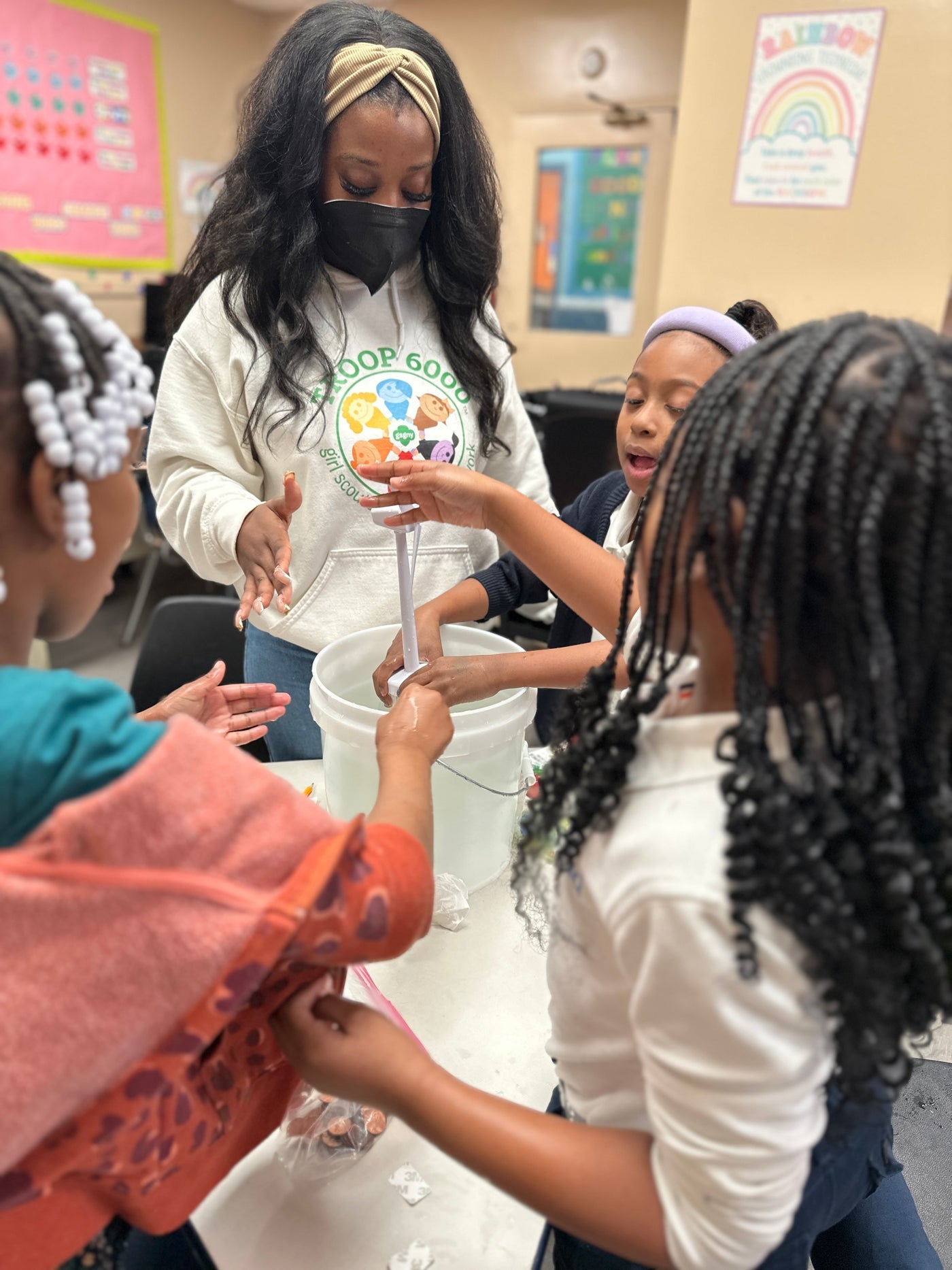 Students working together on a hands-on activity around a water bucket at a WhyMaker program.