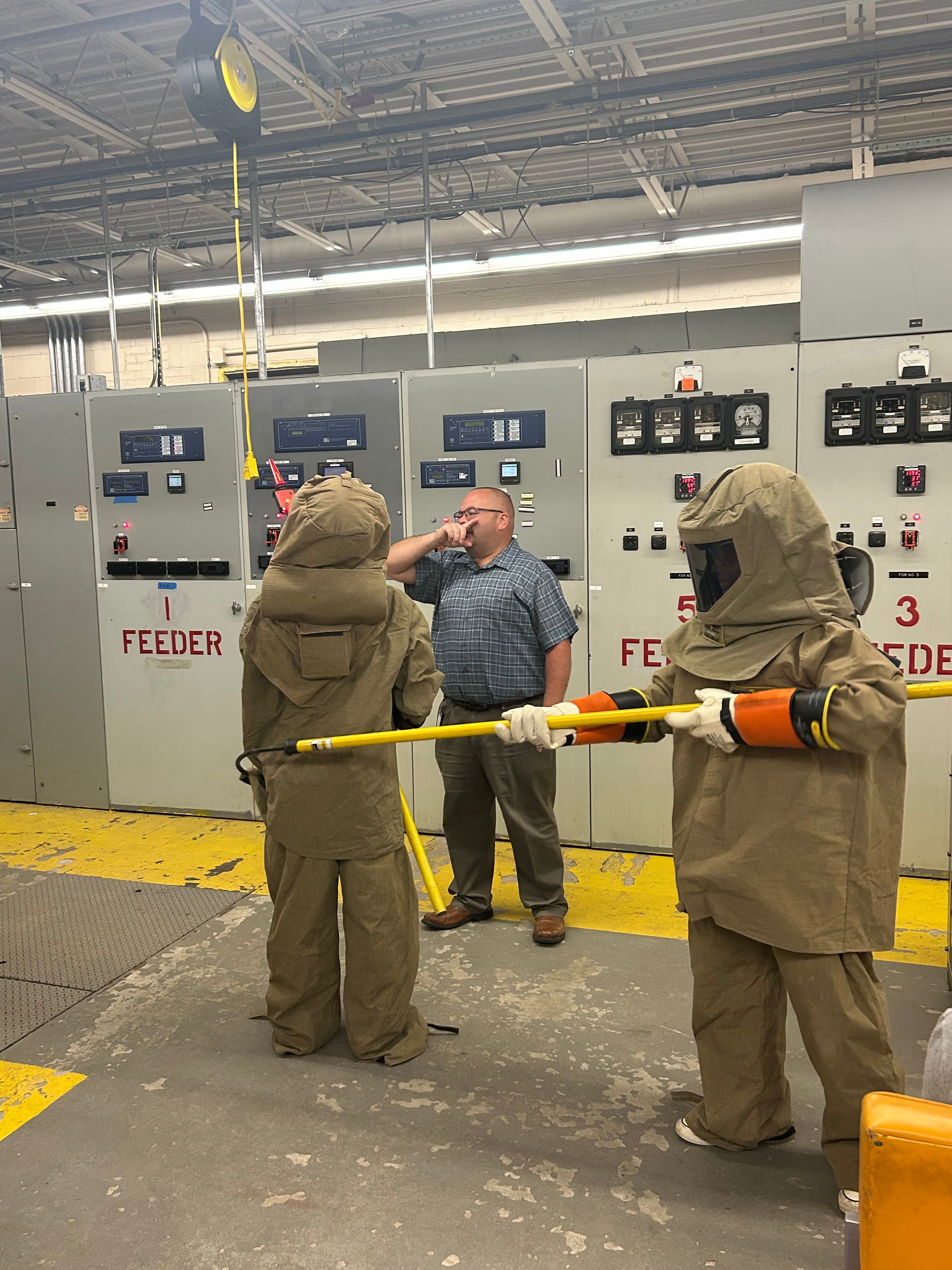 Students trying on arc flash protective gear at a substation