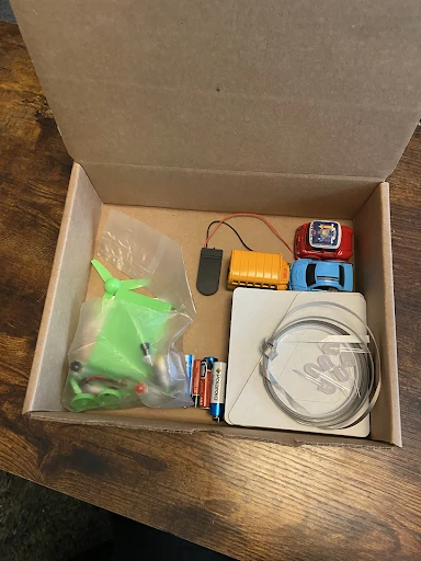 Open EV classroom kit with model cars and battery pack